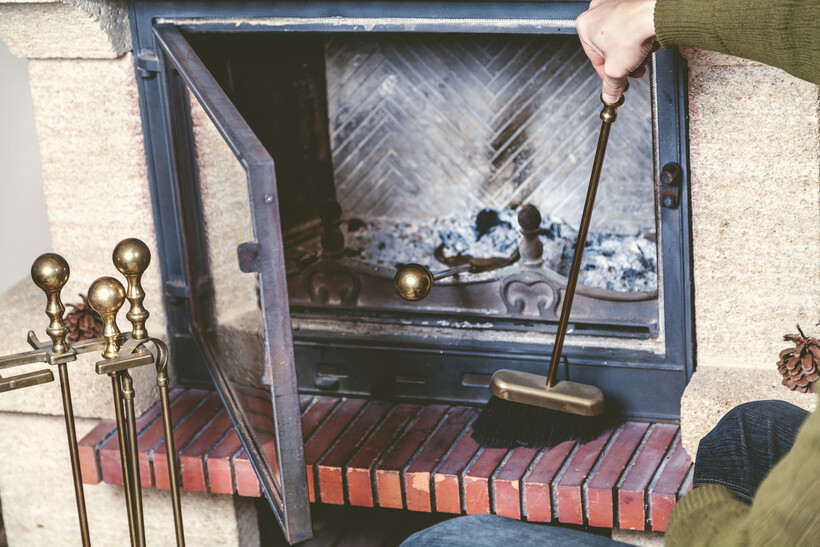 A homeowner brushing built-up soot from the inside of a fireplace. - fireplace installation