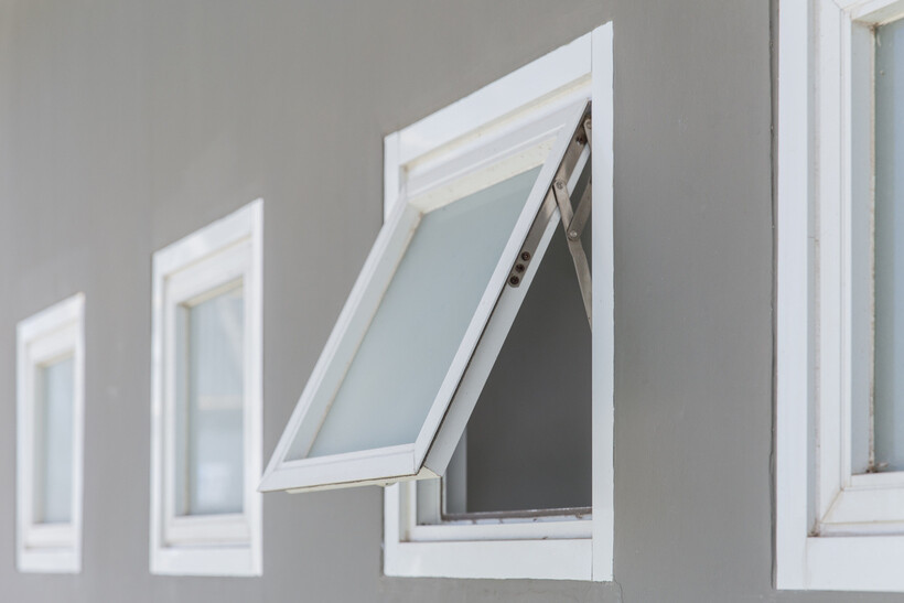 An aluminium awning window opened outward on a modern home exterior. - aluminium windows cost