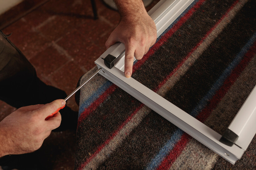 Close-up of hands assembling an aluminium window frame in a workshop. - aluminium windows cost