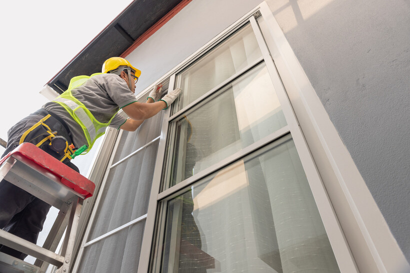 Tradesperson adjusting the rail wheel on an aluminium sliding window. - aluminium windows cost