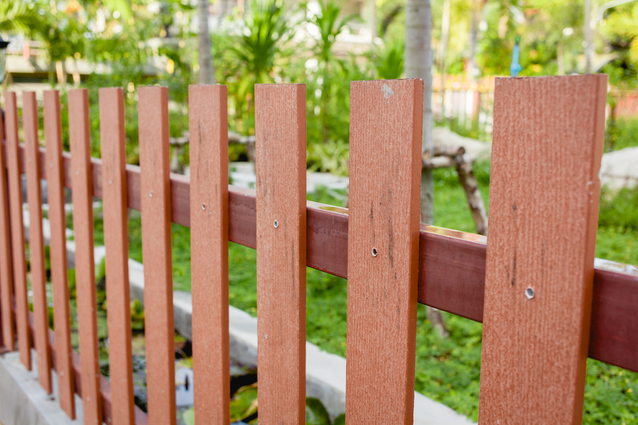 An outdoor privacy screen using vertical wood pickets with a warm neutral stain finish. - garden fencing ideas