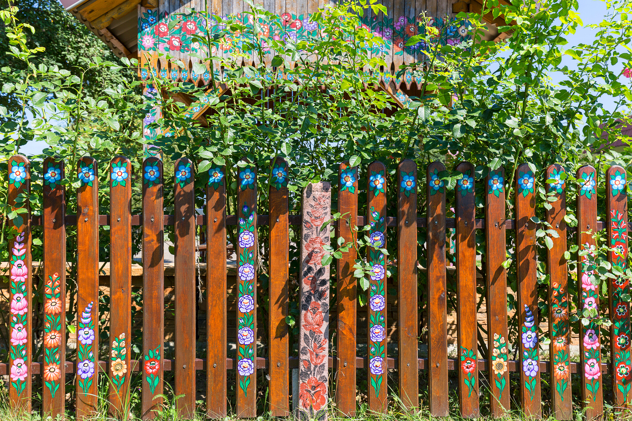 An outdoor garden fence showcasing intricate custom floral murals on wooden slats. - garden fencing ideas
