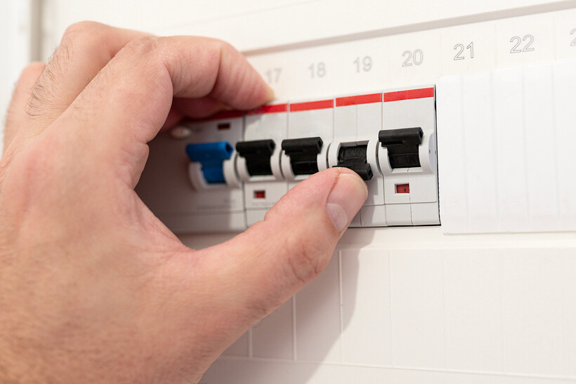 A hand flicking a circuit breaker back to the on position after a trip. - how to use switchboard