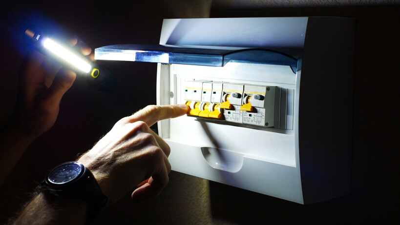 A person switching off multiple levers on an electrical panel during a power check. - how to use switchboard