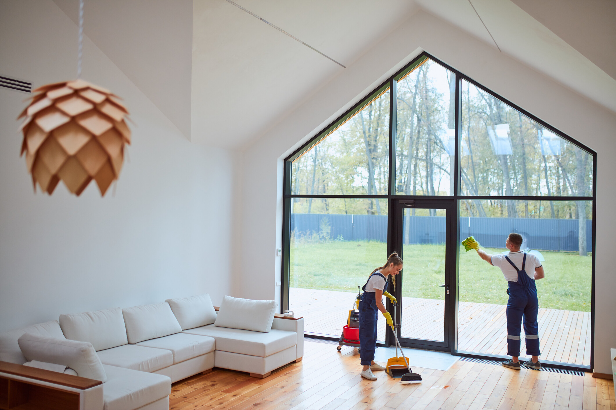 Housekeeping service staff sweeping high-end wood flooring in a large contemporary home. - house cleaning cost