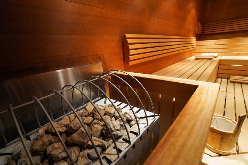 Warm glowing interior of a Finnish sauna with tiered wooden benches and a stone heater. - traditional vs infrared sauna