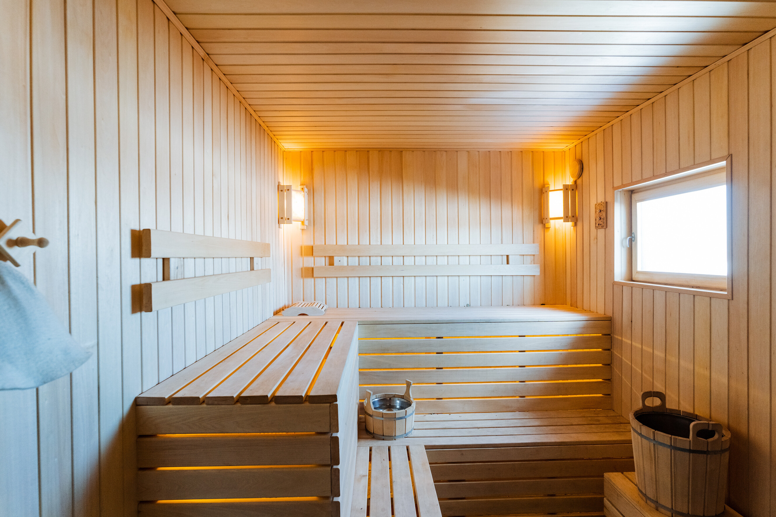Hardwood sauna interior with tiered wooden benches and a natural light window.