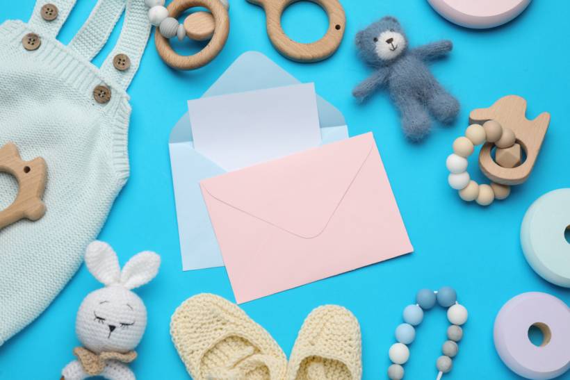 baby shower gift ideas - Newborn essentials with soft toys, wooden rings, beads, and pastel envelopes