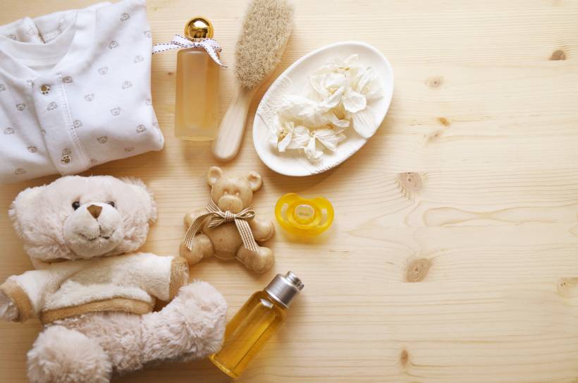 baby shower gift ideas - Baby clothes, teddy bears, pacifier, brush, and care products on wooden surface
