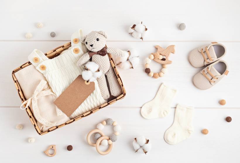 baby shower gift ideas - Neutral baby clothing, knitted teddy bear, shoes, socks, and wooden rattles