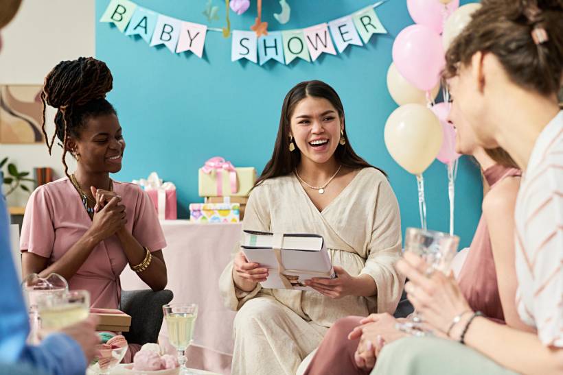 baby shower gift ideas - Expectant mother opening presents with friends at a decorated baby shower