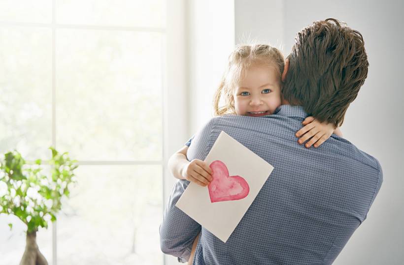 Father's Day gift ideas - Father hugging young daughter holding a handmade heart card