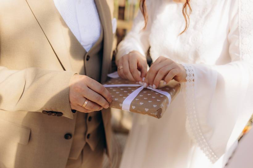 wedding gift ideas - Wedding couple holding a wrapped present with white ribbon