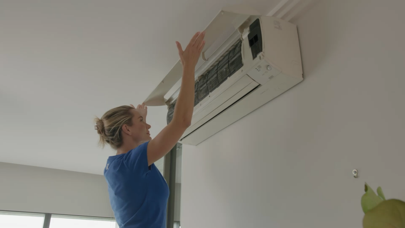 a female professional cleaning tasker opening air conditioner to take out the filter - how to clean air conditioner filter