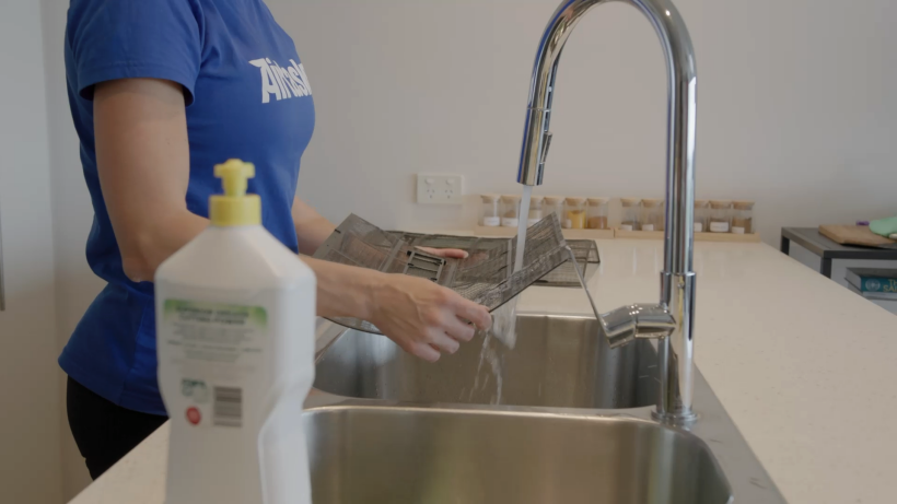 professional cleaner by the sink washing the air con filter to clean it - how to clean air conditioner