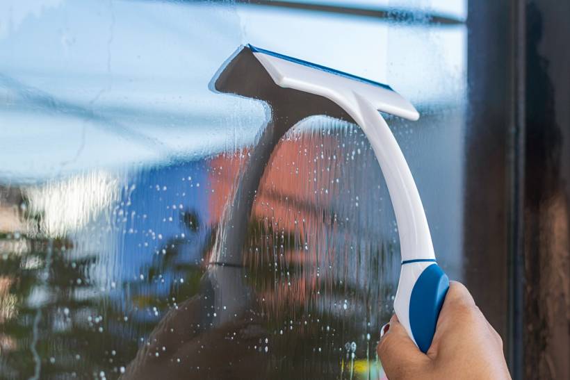 how much does window cleaning cost - Close-up of manual window cleaning with a compact squeegee