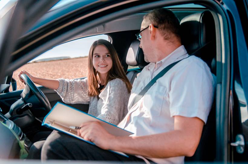 how much do driving lessons cost - Young learner behind the wheel during an in-car driving lesson