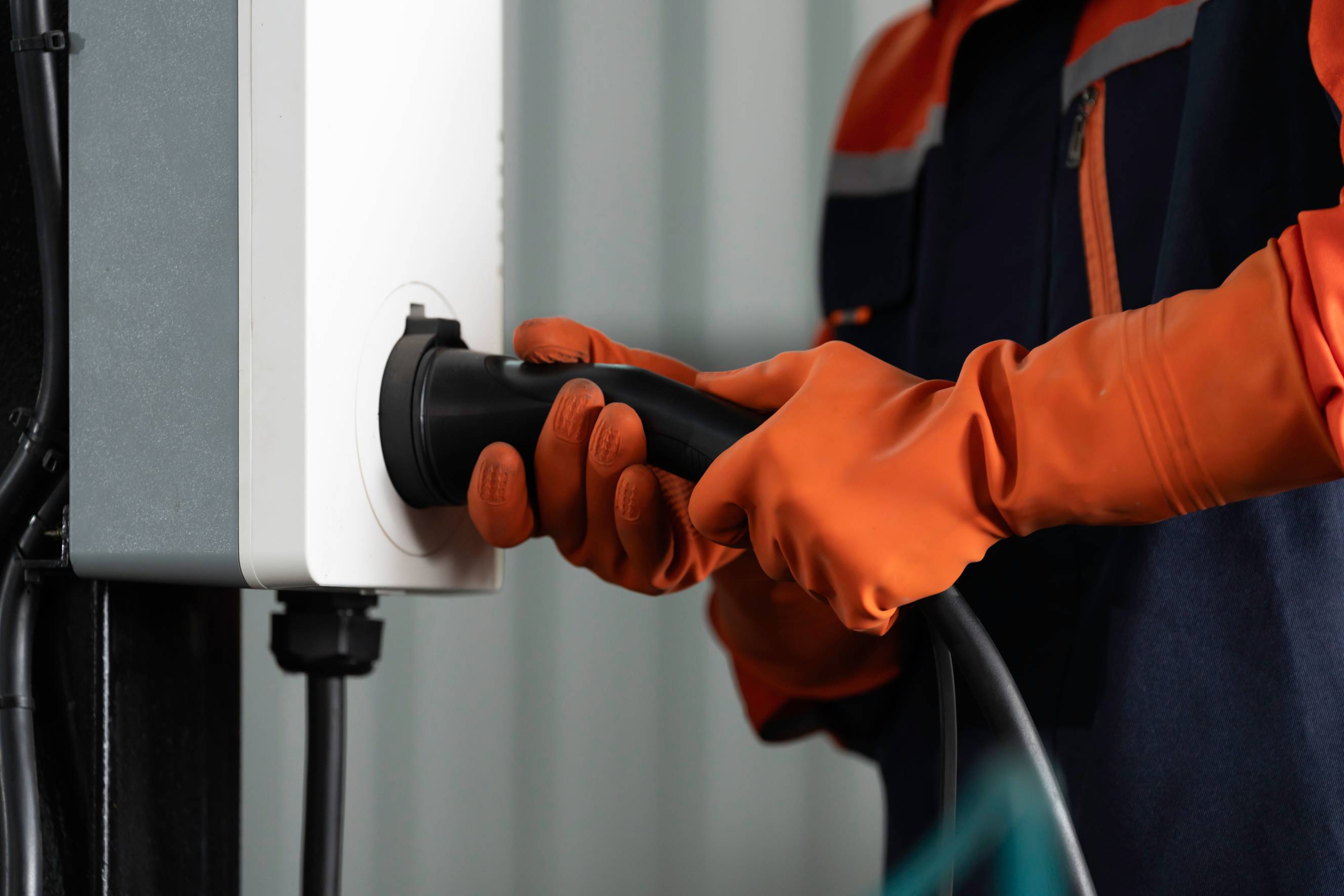 An EV charger installer inserting and checking an electric vehicle charging cable plug into a station socket