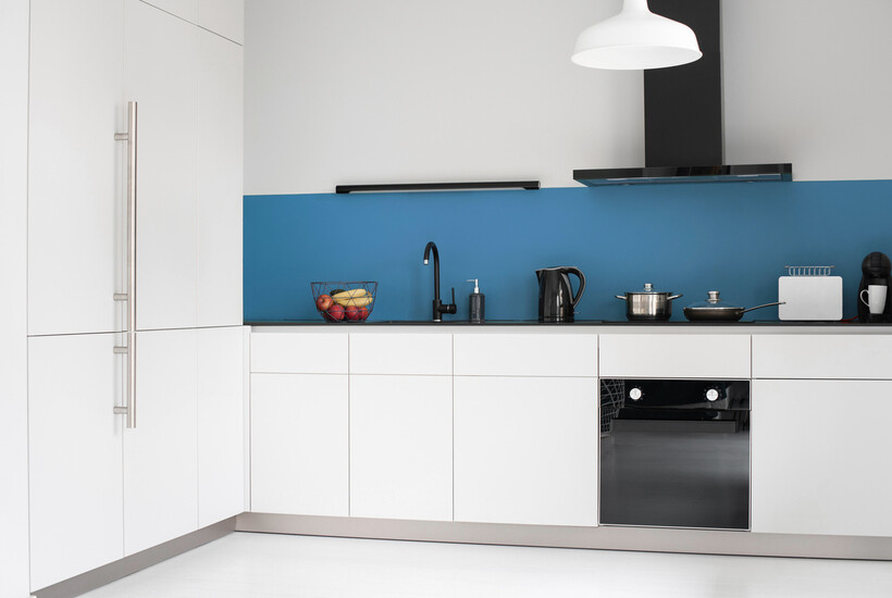 Blue colour-panelled splashback contrasting against white cabinetry and dark benchtop. - kitchen splashback ideas