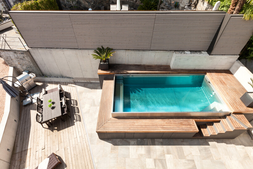 Overhead view of a compact pool with timber decking and a tiled concrete surround. - can you tile over pebblecrete