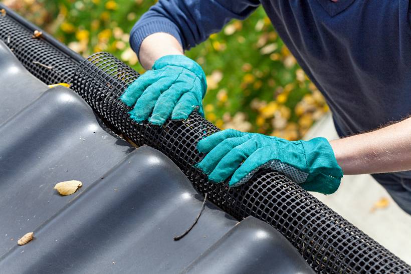 gutter guard installation cost - Black mesh gutter guard secured along the edge of roof tiles