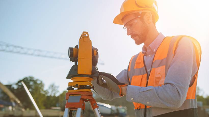 land survey cost - Surveyor operating total station at construction site