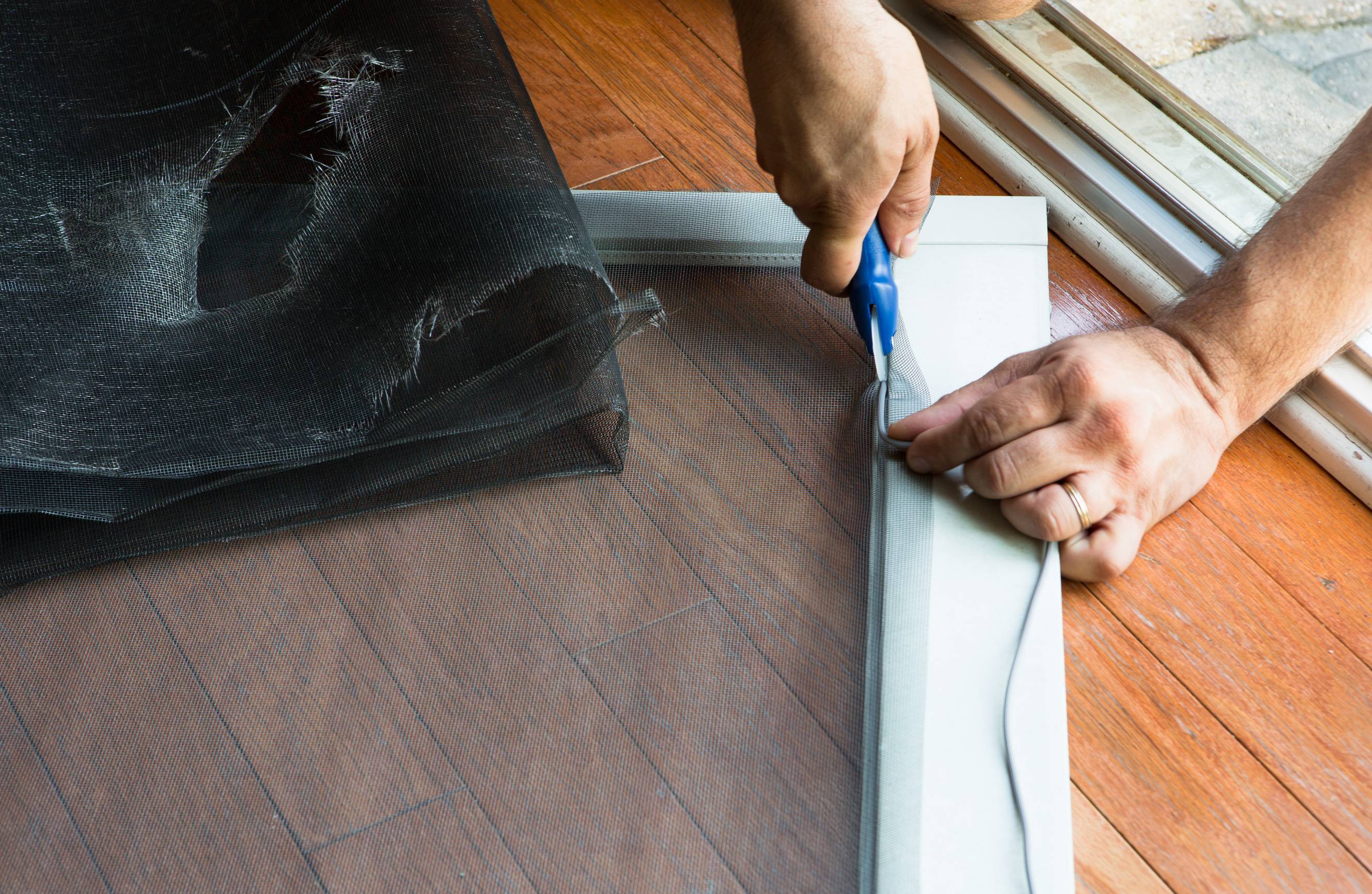 A Tasker doing security door mesh repair and replacing an old, ripped security door mesh