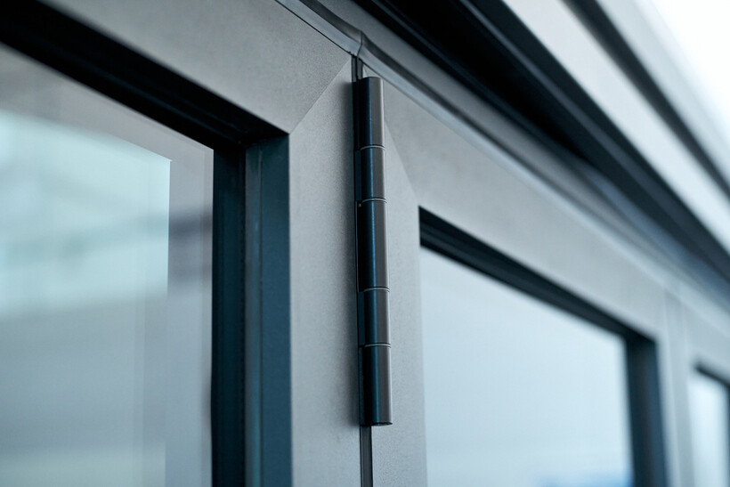 Close-up of dark hardware lining the edge of a modern aluminium bifold door panel. - bifold door installation cost