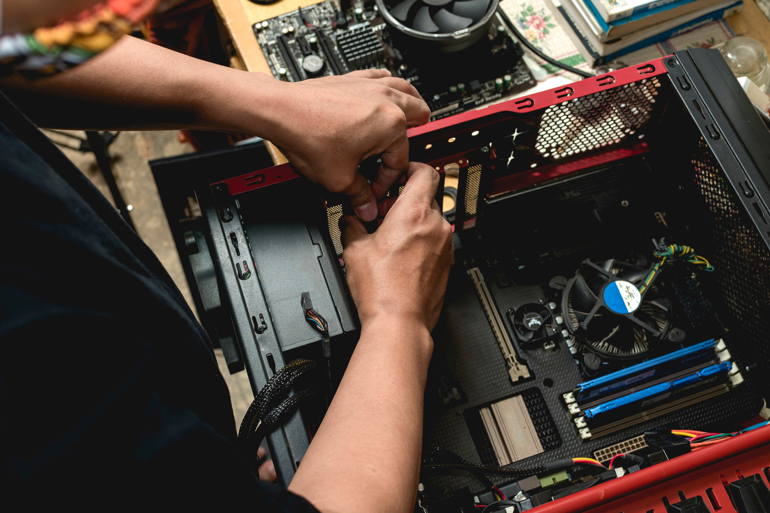 A repairer adjusting internal components inside a red desktop computer case.
