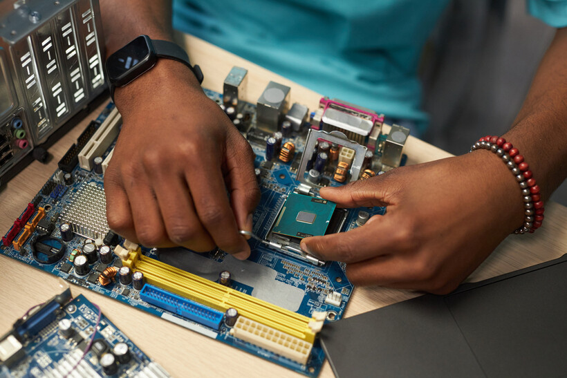 Hands carefully placing a processor chip into its motherboard socket. - computer repair cost