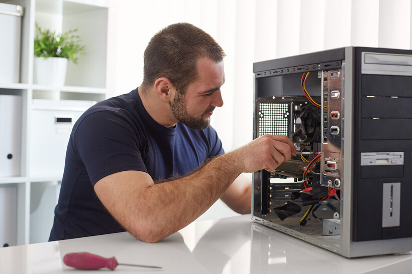 A repairer inspecting internal components of an open desktop computer. - computer repair cost