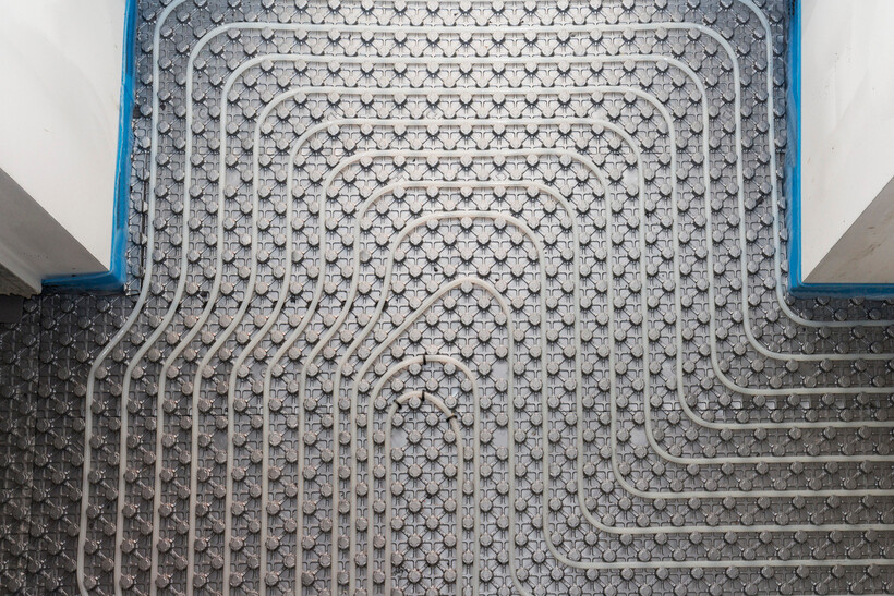 An overhead view showing heating pipe looping in tight concentric rows across a small room. - underfloor heating installation cost