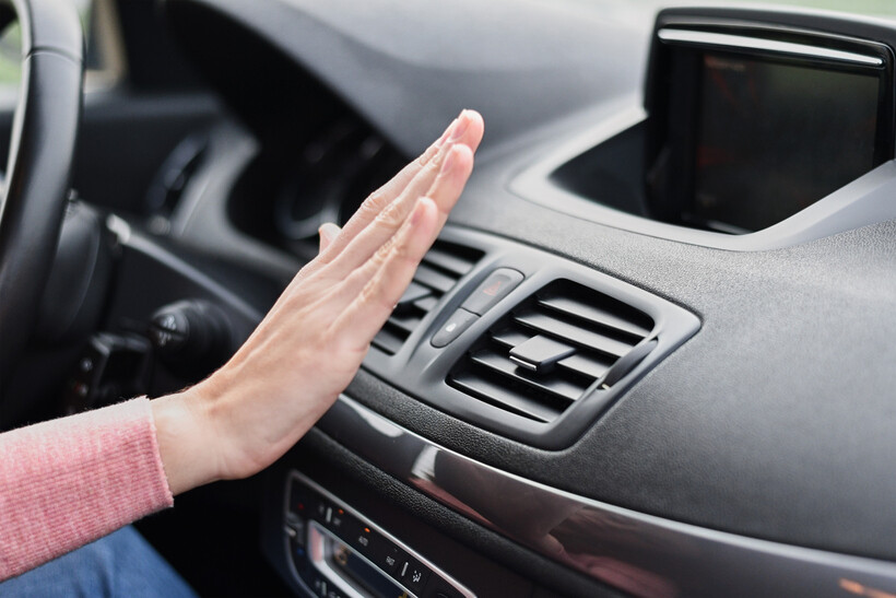 A driver checks air conditioning airflow by holding a hand to the vents. - car aircon regas cost