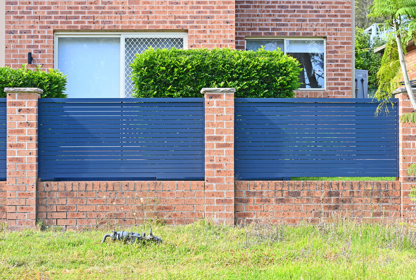 A modern brick fence combines brick piers with dark aluminium slat infill. - brick fencing cost