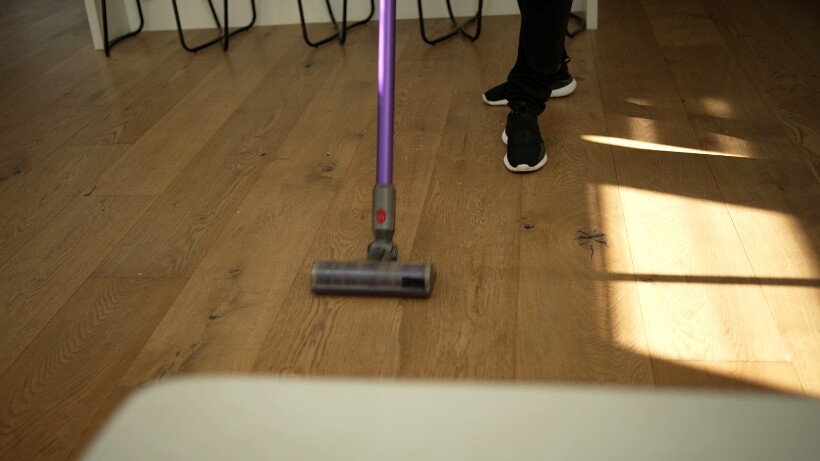 Vacuuming a wooden floor to remove dust and dirt