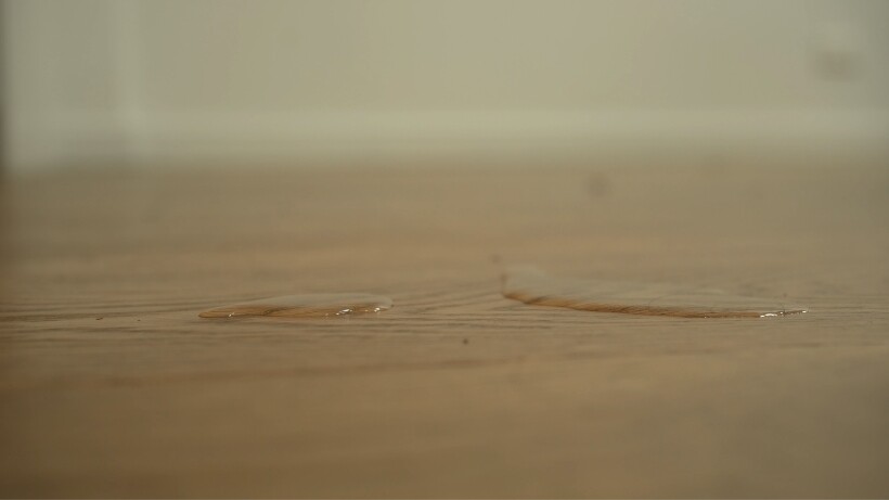Testing a wooden floor with water drops to check if it's sealed