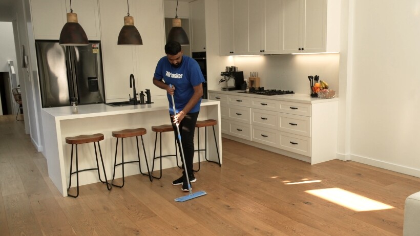 A professional cleaner mopping wooden floors in a modern kitchen