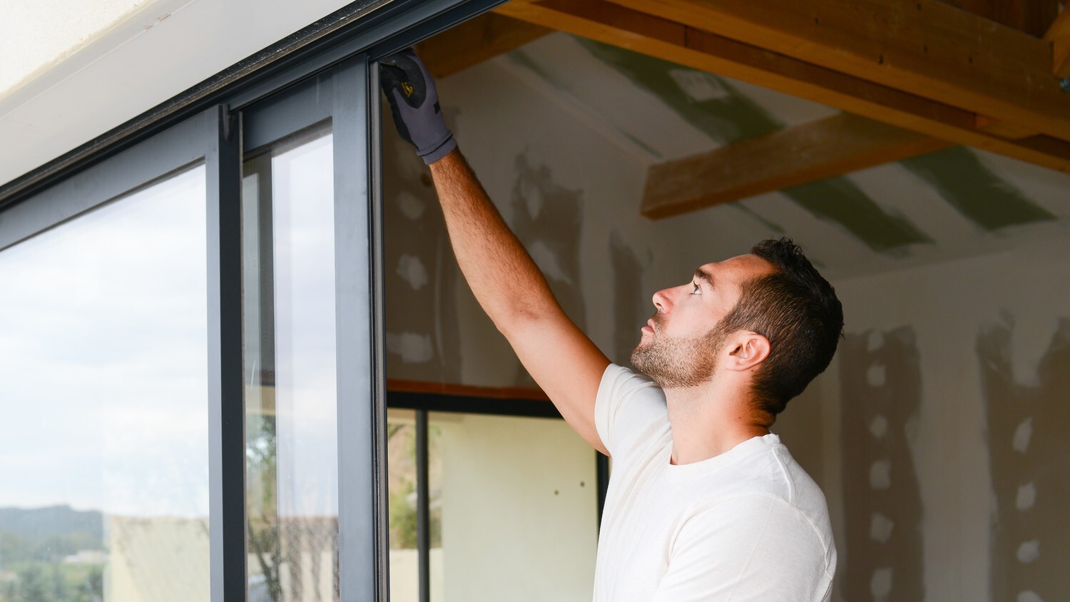 A person wearing gloves, checking the sliding the glass door frame