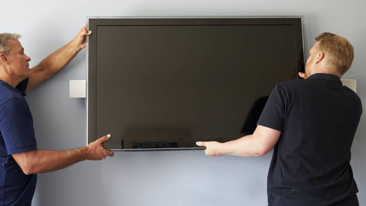 Home theatre technicians installing a TV on a wall