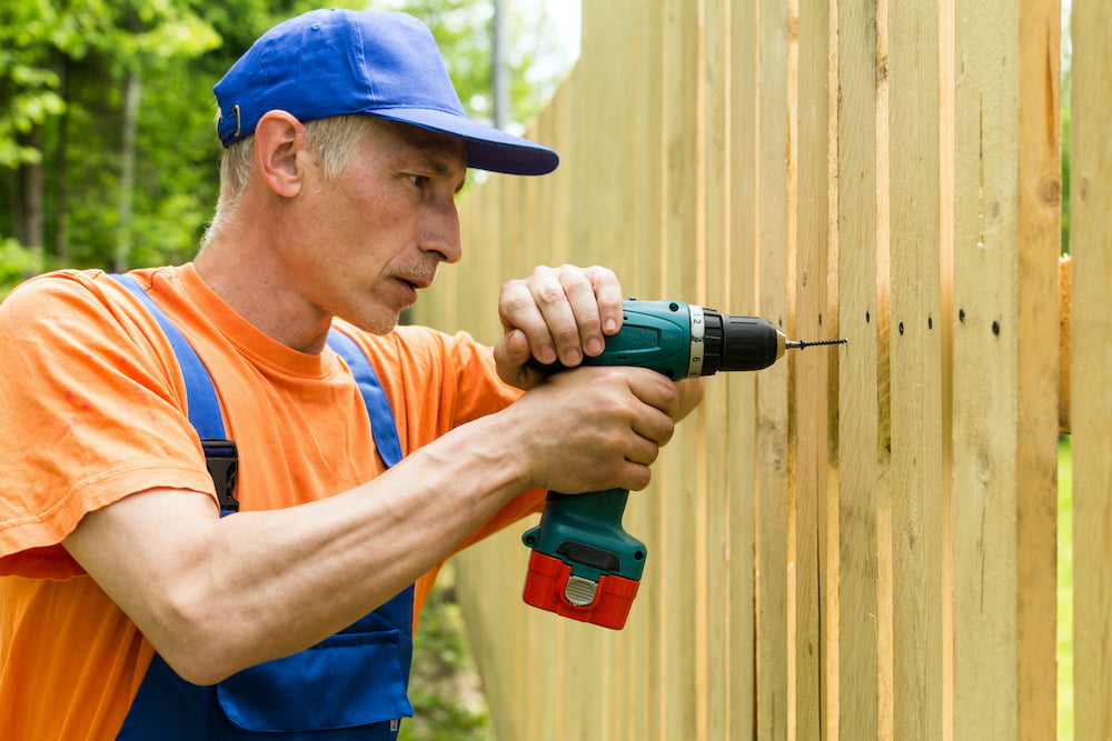 a handyman repairing a wooden fence