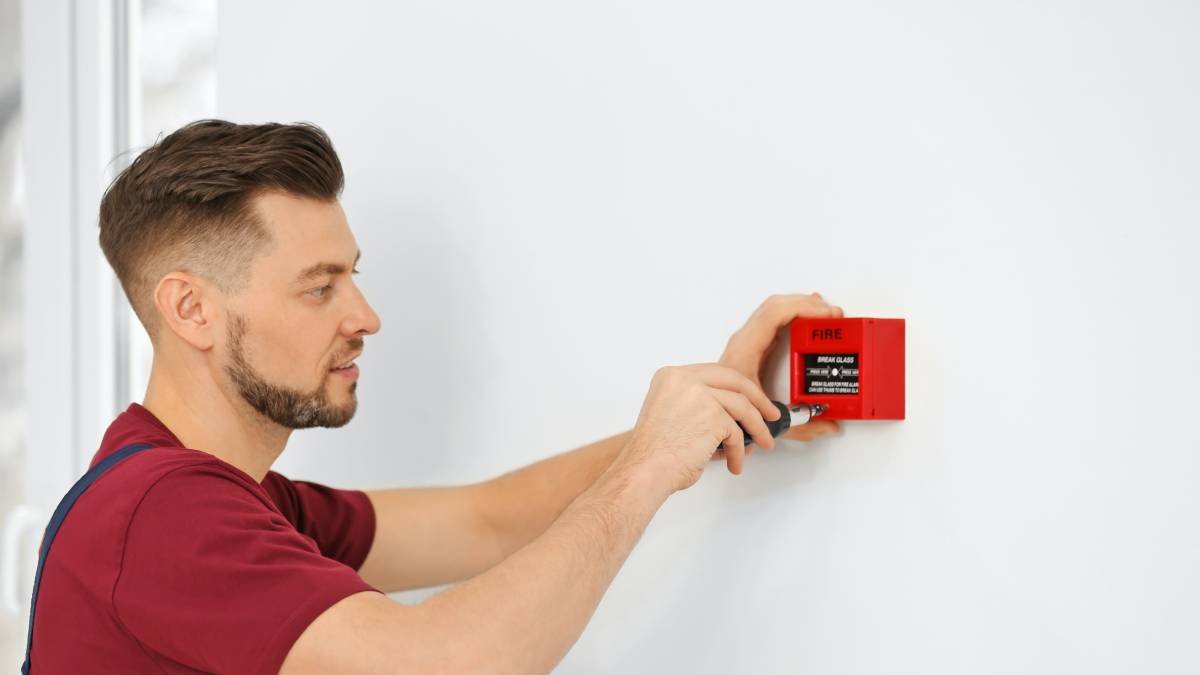 a handyman setting up a fire alarm