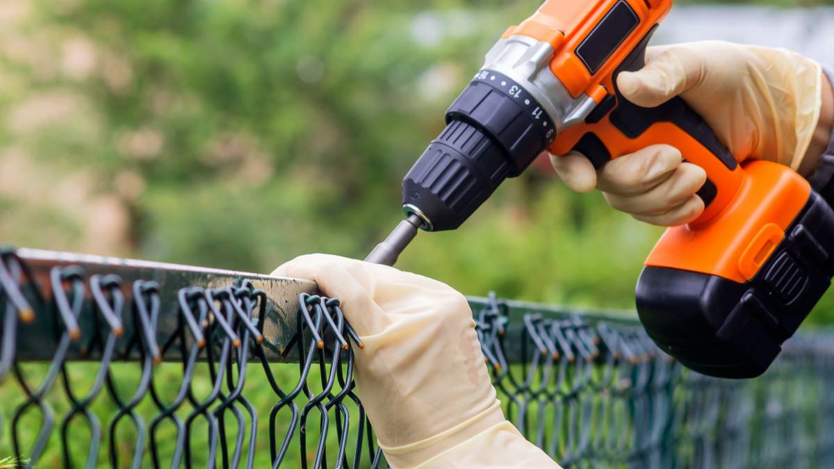 a man repairing a chain-link fence