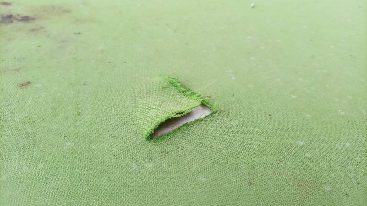 Pool table refelting cost - close-up of damaged green pool table felt.