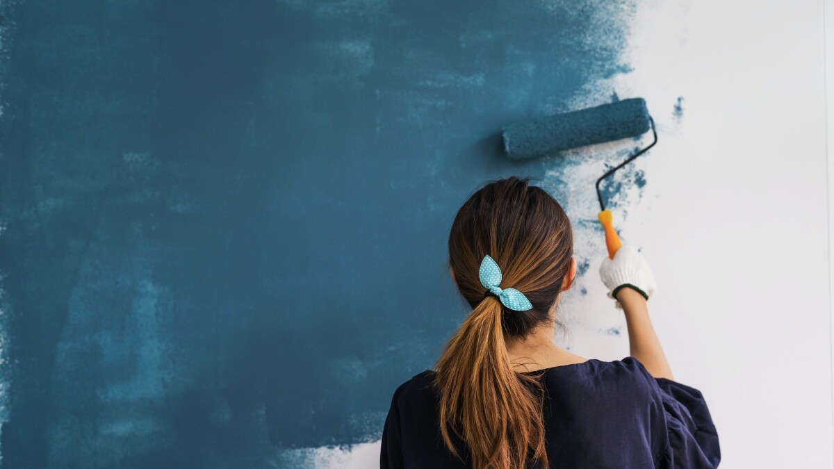 woman holding roller painting walls blue
