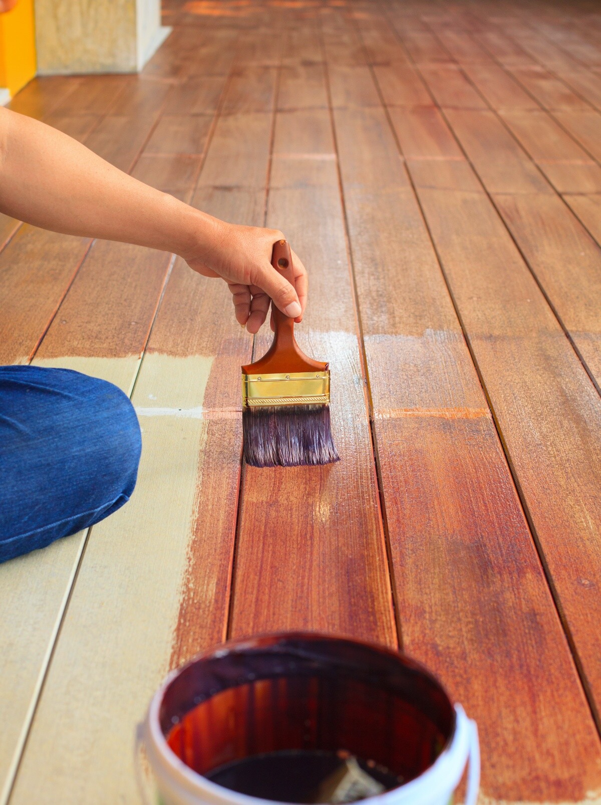person holding brush painting deck