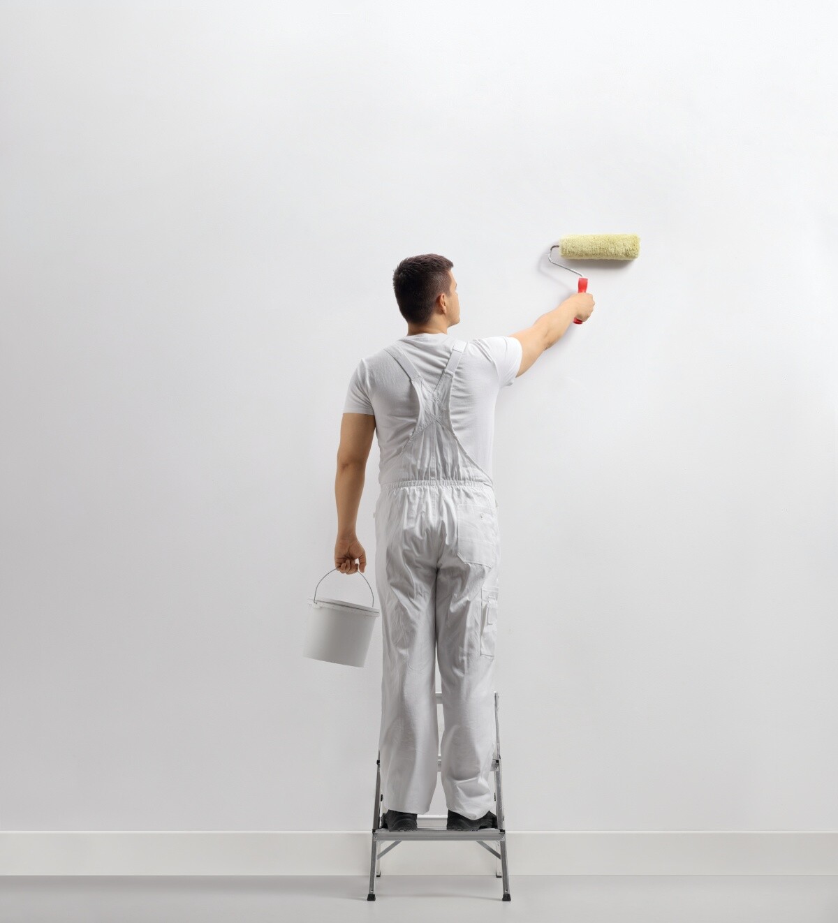 man wearing white using roller to paint white wall