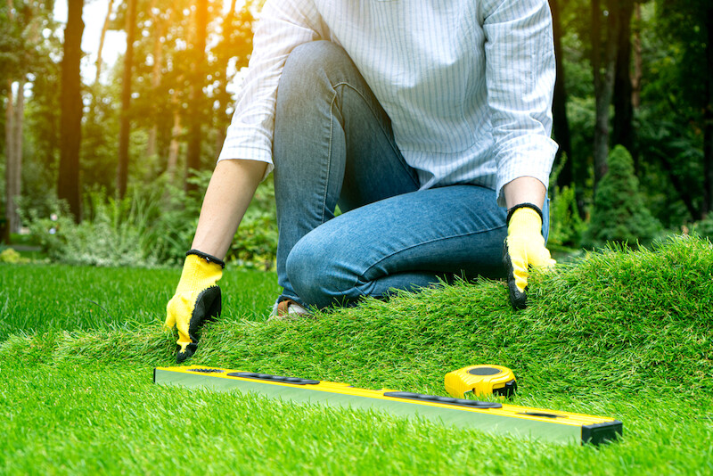 a woman landscaper installing synthetic grass