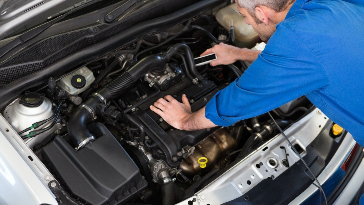 mechanic working under hood of a car