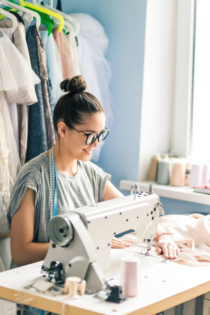 a woman using a white sewing machine for dress creation