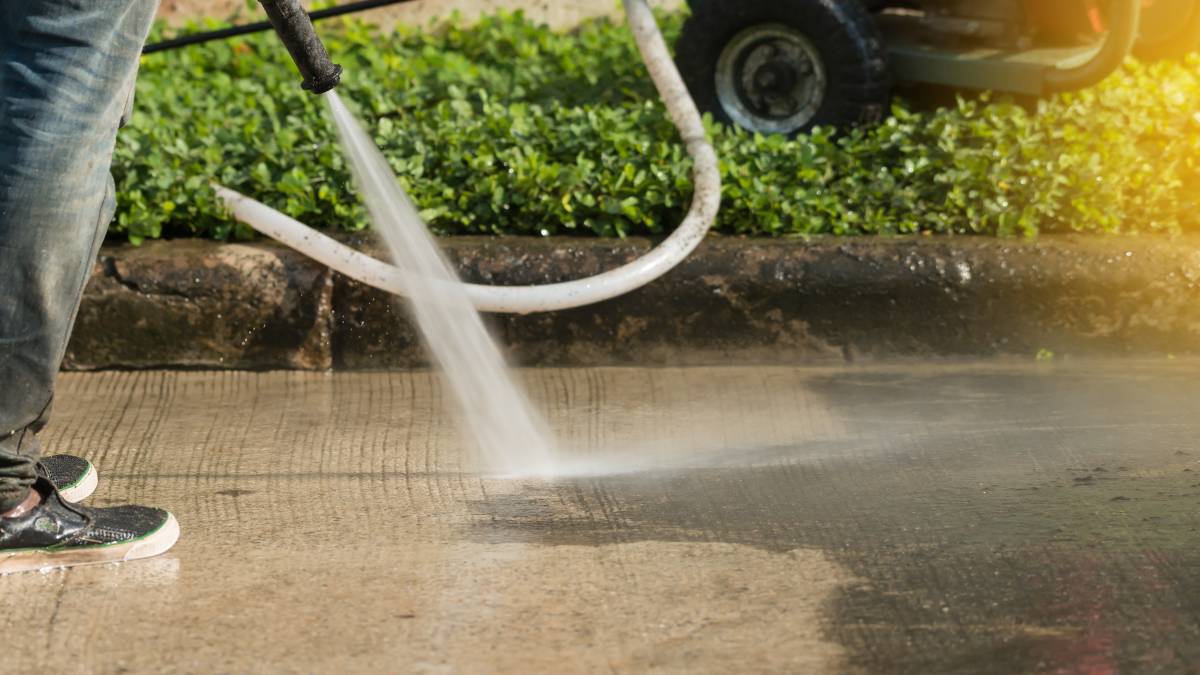 man cleaning driveway with pressure washer